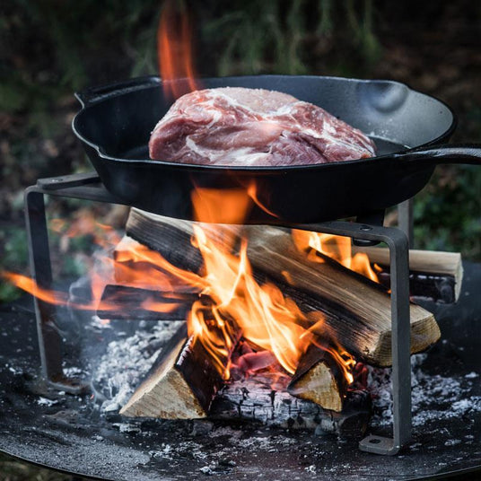 Fleisch in einer robusten Gusseisenpfanne von Petromax, langsam über einem offenen Lagerfeuer gegart