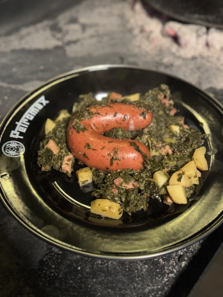 Herzhafter Grünkohl aus dem Dutch Oven mit Kassler, Mettwürsten, Kartoffeln und knusprigem Speck, frisch über dem Feuer zubereitet