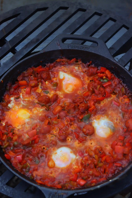 Würzige Merguez Shakshuka aus der gusseisernen Pfanne mit Tomaten, Paprika, Eiern und frischen Kräutern, direkt vom Grill serviert