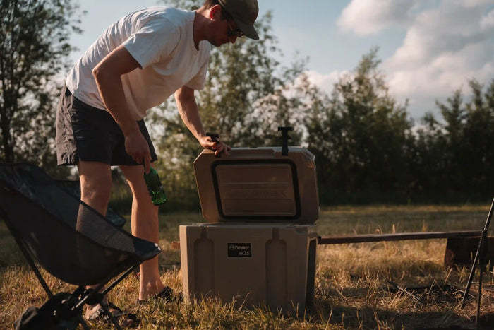 Mann stellt eine Flasche in den Kühlbox kx25 draußen