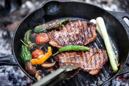 Frisch gegrilltes Gemüse und Fleisch auf einer gusseisernen Grill-Feuerpfanne